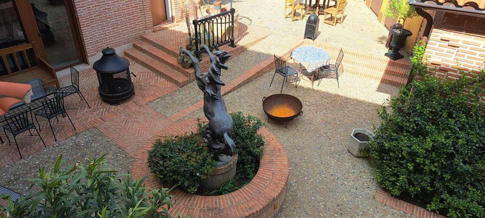 A courtyard with a statue, outdoor seating, and a fire pit.