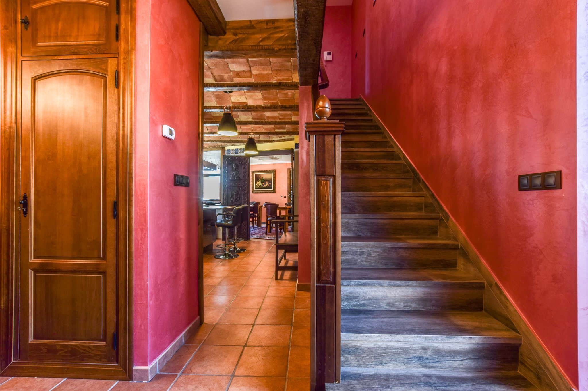 A wooden door, a staircase, and a red wall.