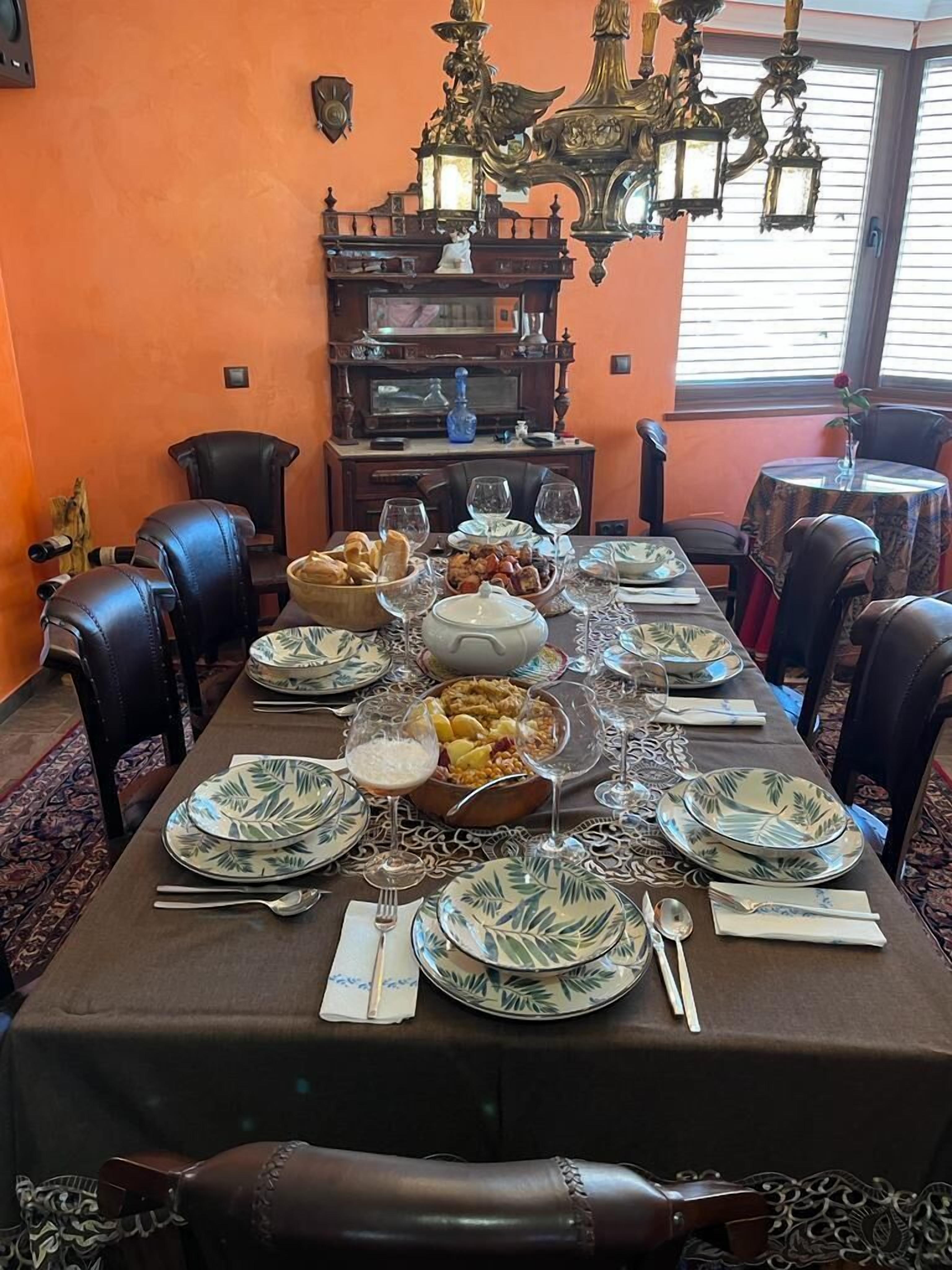 Comedor con una mesa larga dispuesta para una comida, rodeado de sillas de cuero.