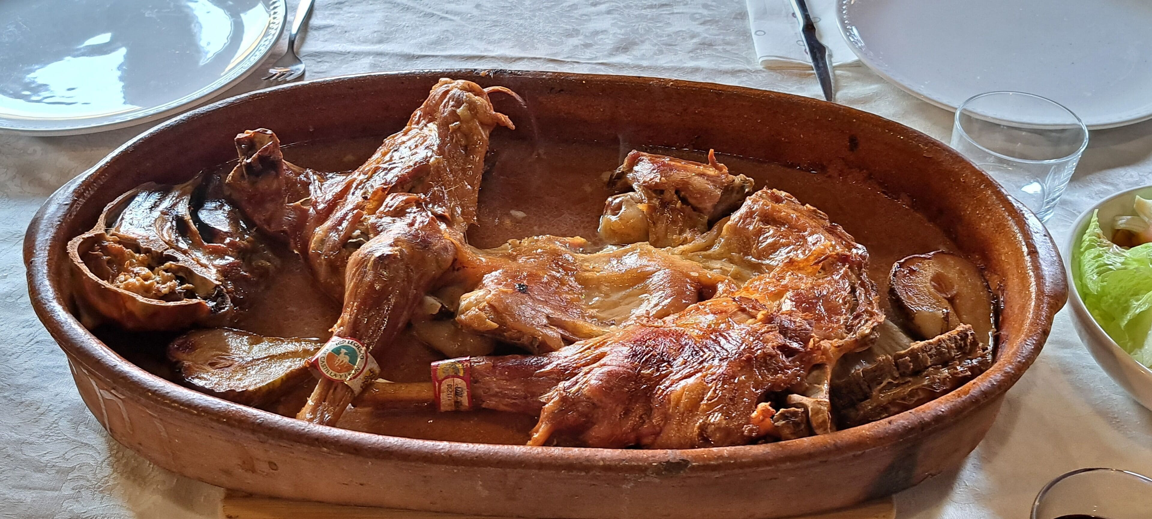 Un plato grande de cerámica con pollo asado sobre una mesa.