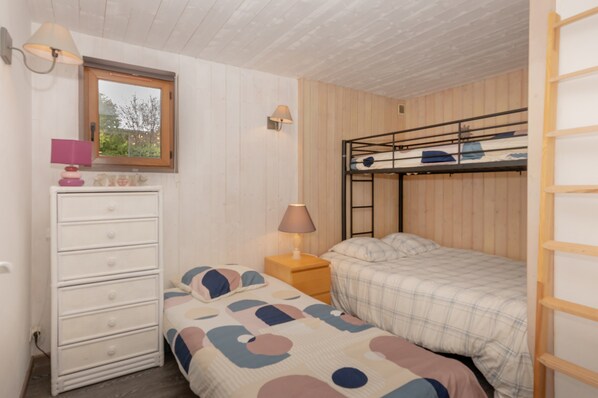 Un dormitorio con literas, un aparador, una lámpara y una ventana.