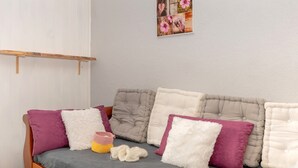 A bed with a grey mattress, multiple pillows, and a knitted item on the bed.