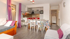 A compact living space with a dining area, kitchenette, and a bed with a headboard.