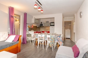 Un espace de vie compact comprenant un coin repas, une kitchenette et un lit avec une tête de lit.