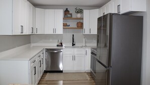 A modern kitchen with white cabinets, stainless steel appliances, and a wooden countertop. - 3-bedroom house in perfect location. 6 minutes from the Beach. (Vero Beach)