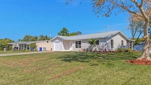 A single-story house with a covered porch, a garage, and a well-maintained lawn. - 3-bedroom house in perfect location. 6 minutes from the Beach. (Vero Beach)