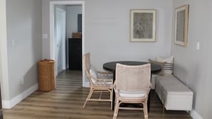 A dining area with wicker chairs, a round table, and a bench. - 3-bedroom house in perfect location. 6 minutes from the Beach. (Vero Beach)
