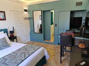 A hotel room with a large bed, a desk with a chair, a mirror, and a small kitchenette. - Apartment-Luxury-Garden view-Private Bathroom (Troyes)