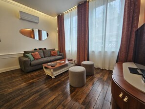 A living room with a sofa, ottoman, and a wooden coffee table. - Apartment-Luxury-Garden view-Private Bathroom (Troyes)