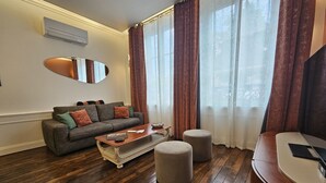 A living room with a sofa, ottoman, and a wooden coffee table. - Loft-Executive-Garden view-Private Bathroom (Troyes)