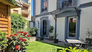A courtyard with a neatly trimmed lawn, potted plants, and outdoor furniture. - Apartment-Luxury-Private Bathroom-Garden view-Rdc A (Troyes)