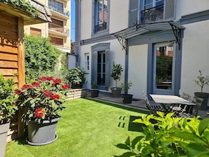 A courtyard with a neatly trimmed lawn, potted plants, and outdoor furniture. - Apartment-Luxury-Private Bathroom-Garden view-Rdc A (Troyes)