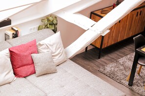 A cozy living area with a sofa, cushions, a wooden cabinet, and a plant. - Apartment-Luxury-Private Bathroom-Garden view-Rdc A (Troyes)