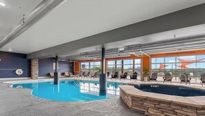 Une piscine intérieure dotée de chaises longues et offrant une vue sur l’extérieur.