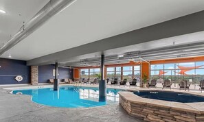 Piscina interior con sillones de descanso y vistas al exterior.