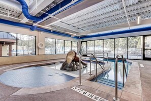 An indoor swimming pool with a stone sculpture, clear windows, and a ceiling with visible ductwork. - Ski In/Out Studio, 200 yds from Lift, 3 Hot Tubs! (Breckenridge)