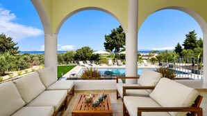 A covered outdoor seating area with a pool and a view of the sea. - Sunset View Paradisi Villa (Rhodes)