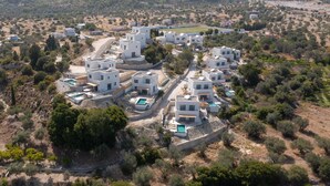 Zona residenziale con edifici moderni e bianchi, alcuni con piscine, immersa in un paesaggio collinare e arido.