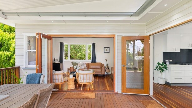 A modern living room with a wooden deck, a sofa set, and a dining area. - Blue View Cottage! Simply Perfect! (Centenary Heights)