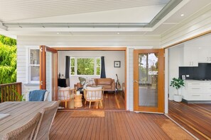 Un salon moderne avec une terrasse en bois, un ensemble de canapés et un coin repas.