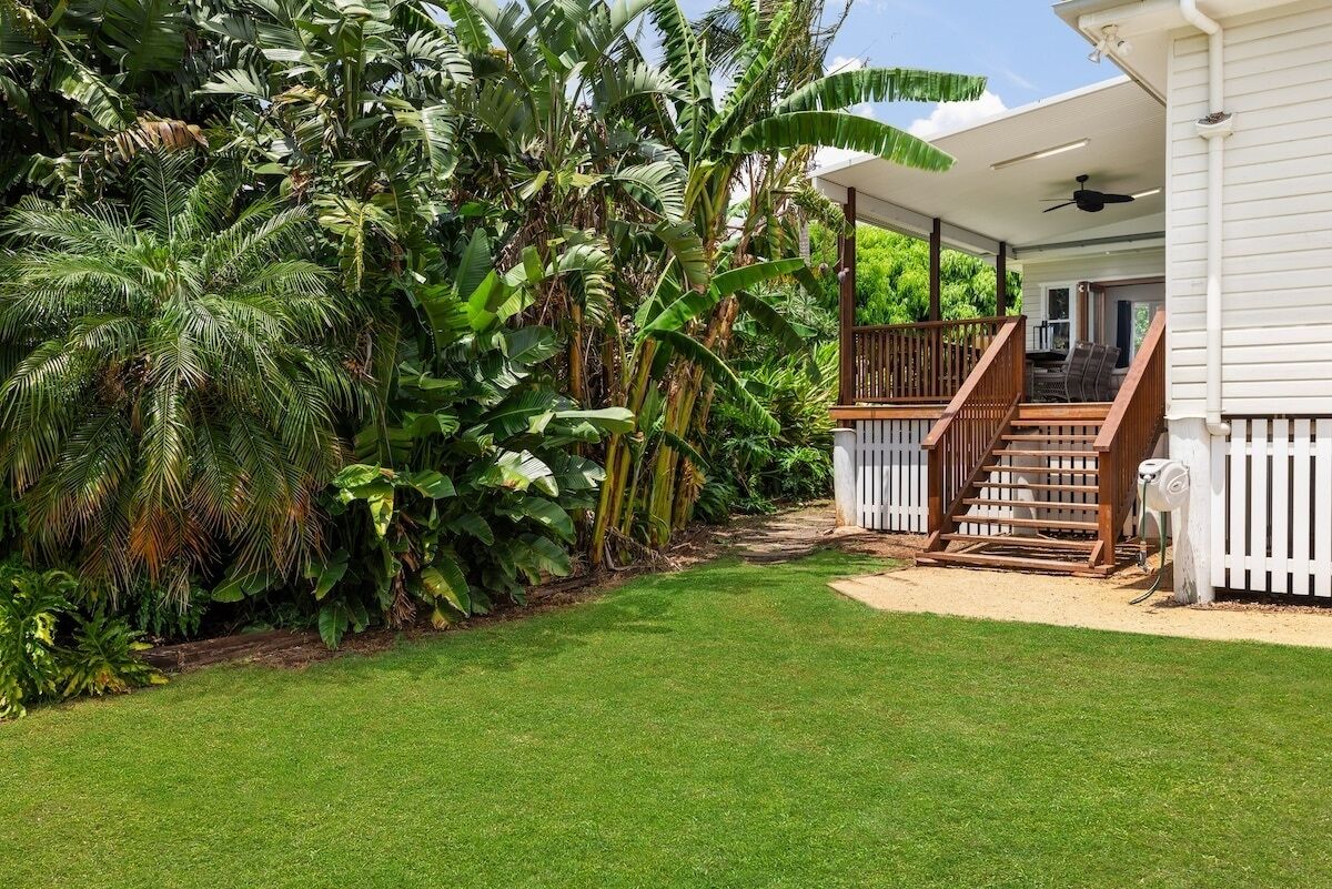 A house with a covered porch, a staircase, and a well-maintained lawn.
