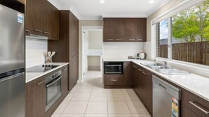 A modern kitchen with dark wood cabinets, stainless steel appliances, and a large window offering a view of the outdoors. - Middle Ridge Retreat – Walk to Shops & Parks! (Middle Ridge)