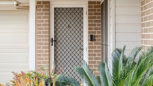 A house entrance with a metal gate, brick walls, and a garage door. - Middle Ridge Retreat – Walk to Shops & Parks! (Middle Ridge)