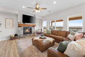 A spacious living room with a fireplace, leather sofa, and a large TV.