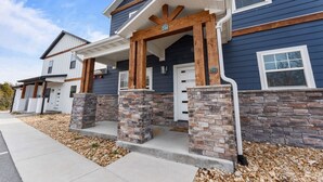 A two-story house with a stone foundation, a porch with wooden posts, and a blue exterior. - Gorgeous Lake View | Indoor Pool Access | Hot Tub (Branson)