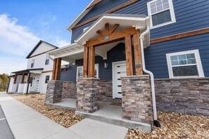 A two-story house with a stone foundation, a porch with wooden posts, and a blue exterior.