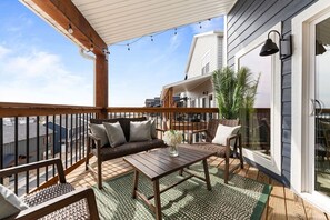 A covered balcony with a wooden bench, a table, and a potted plant.