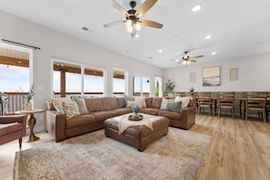 A spacious living room with a large sectional sofa, a coffee table, and a dining area with wooden chairs.
