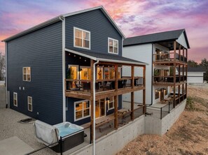 A two-story house with a balcony, a hot tub, and a deck area. - Gorgeous Lake View | Indoor Pool Access | Hot Tub (Branson)