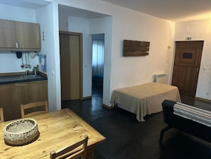 A compact room with a bed, a small kitchenette, a dining table, and a chair. - Cabana Apartment with Shared Pool (Castelo de Vide)
