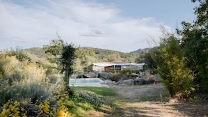 A house with a pool, surrounded by natural vegetation and hills. - Cabana Apartment with Shared Pool (Castelo de Vide)