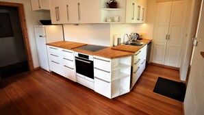 A compact kitchen with white cabinets, a wooden countertop, and a built-in oven. - Melody - Joli 2 pièces | La Sage (La Sage)