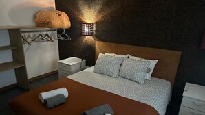 Une chambre à coucher moderne, comprenant un lit, des tables de chevet, une armoire et un luminaire fixé au mur.