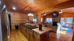A spacious kitchen with wooden cabinets, a central island, and pendant lighting. - Cottage on Cypress Bay Near Paris Landing State Park (Buchanan)