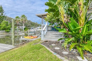 A dock with kayaks, a wooden deck, and lush greenery.