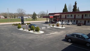 A motel with a parking lot, several cars parked, and a building with a red roof. - Starlite Motor Inn (Absecon)
