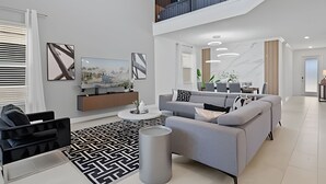 Een moderne woonkamer met een grijze bank, een zwart-wit tapijt met patroon en een flatscreen televisie op een houten dressoir.