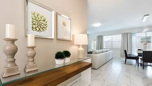 Un moderno vestíbulo de hotel con una recepción, obras de arte enmarcadas, plantas en macetas, un sofá y un comedor.