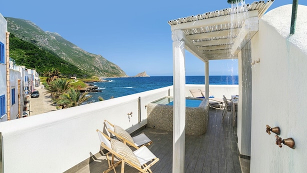 A balcony with a pool, lounge chairs, and a view of the sea. - Hiera - Two Bedroom Villa, Sleeps 4 (Marettimo)