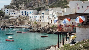 A coastal town with buildings, boats, and a rocky hillside. - Hiera - Two Bedroom Villa, Sleeps 4 (Marettimo)