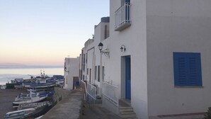 A coastal building with a balcony, a staircase, and a row of boats docked at the beach. - Hiera - Two Bedroom Villa, Sleeps 4 (Marettimo)
