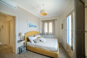 A bedroom with a bed, bedside tables, a lamp, a painting, and a window with curtains.