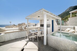 Una terraza en la azotea con piscina, mobiliario exterior y vistas al mar.