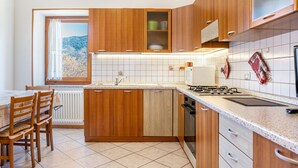Una cocina con armarios de madera, encimera, estufa y ventana con vistas a un paisaje nevado.