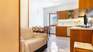 Un espacio habitable compacto con sofá, mesa de comedor y kitchenette.