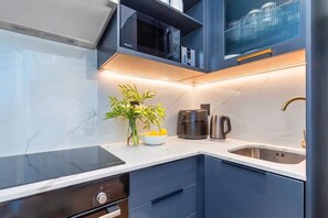 A modern kitchen with a built-in microwave, coffee maker, and kettle.
